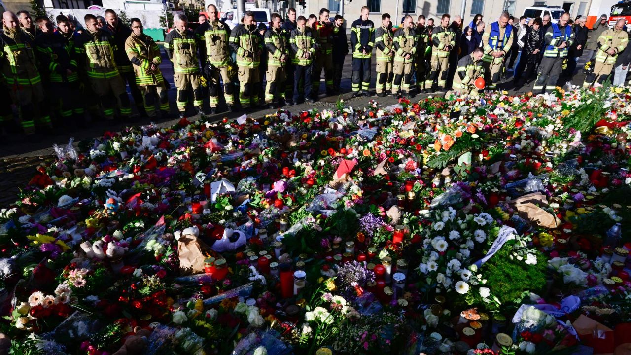 Miembros del cuerpo de bomberos de Magdeburgo se encuentran en un monumento improvisado fuera de la iglesia Johanniskirche (Iglesia de San Juan), cerca del lugar donde se produjo un atropello con un coche en un mercado navideño en Magdeburgo, este de Alemania. | Foto:JOHN MACDOUGALL / AFP