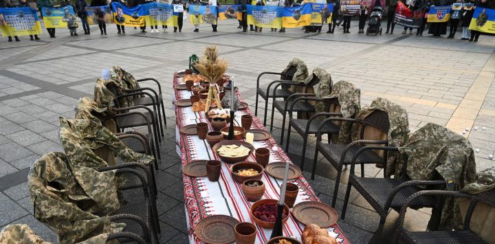 Los uniformes de los soldados cuelgan en sillas vacías junto a una mesa navideña simbólica preparada con platos tradicionales mientras la gente asiste a una manifestación en apoyo de los prisioneros de guerra y los soldados desaparecidos en Lviv, en medio de la invasión rusa de Ucrania.