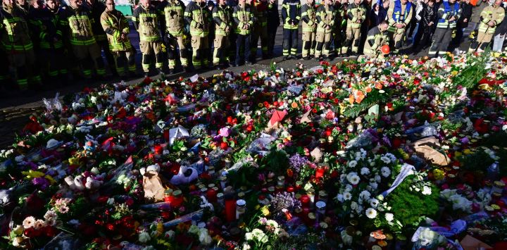 Miembros del cuerpo de bomberos de Magdeburgo se encuentran en un monumento improvisado fuera de la iglesia Johanniskirche (Iglesia de San Juan), cerca del lugar donde se produjo un atropello con un coche en un mercado navideño en Magdeburgo, este de Alemania.