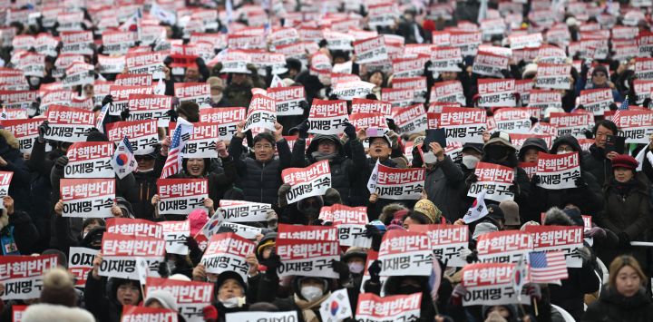 Varias personas sostienen carteles que dicen "Oposición al impeachment, arresten a Lee Jae-myung" mientras participan en una manifestación en apoyo del presidente de Corea del Sur destituido, Yoon Suk Yeol, en el centro de Seúl.