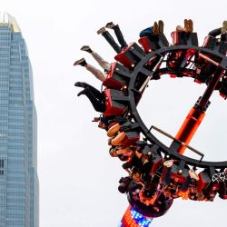 La gente se sube a un mazo de Luna Park frente a la torre del Centro Financiero Internacional (CFI) en Hong Kong. | Foto:Mladen Antonov / AFP