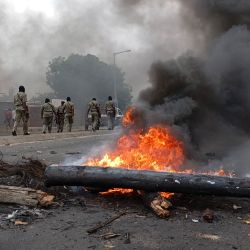 Los peatones pasan junto a una barricada en llamas en Maputo, Mozambique. | Foto:Amilton Neves / AFP