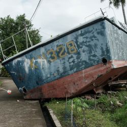 Syafriani, de 41 años, cuya madre sigue desaparecida tras el tsunami del océano Índico de 2004, limpia delante de su casa, donde dos patrulleras encallaron y permanecen preservadas por deseo de la comunidad, en Banda Aceh, en vísperas del aniversario del tsunami. | Foto:Yasuyoshi Chiba / AFP