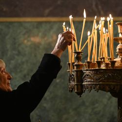 Un creyente cristiano ortodoxo enciende una vela durante una misa de Navidad en la catedral de Alexander Nevski, con su cúpula dorada, en Sofía, Bulgaria. | Foto:NIKOLAY DOYCHINOV / AFP