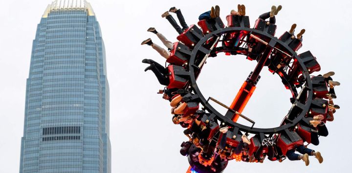 La gente se sube a un mazo de Luna Park frente a la torre del Centro Financiero Internacional (CFI) en Hong Kong.