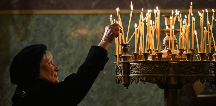 Un creyente cristiano ortodoxo enciende una vela durante una misa de Navidad en la catedral de Alexander Nevski, con su cúpula dorada, en Sofía, Bulgaria.