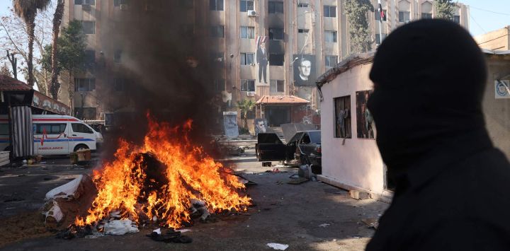 Un hombre observa cómo arde una pila de drogas ilícitas, mientras las nuevas autoridades sirias queman drogas supuestamente confiscadas a una división de seguridad, en Damasco, Siria.