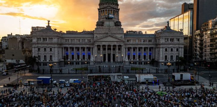 Vista aérea que muestra a voluntarios y personas sin hogar participando en una cena solidaria navideña llamada 'Ninguna Familia Sin Navidad' frente al Congreso de la Nación en Buenos Aires.