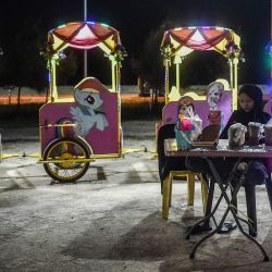 Una vendedora utiliza un teléfono móvil mientras espera a los clientes en Pantai Batu Buruk en Kuala Terengganu, Malasia. | Foto:Arif Kartono / AFP