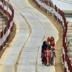 Mujeres y niños caminan sobre un puente flotante sobre el río Ganges, en una fría tarde de invierno, antes del festival Maha Kumbh Mela en Prayagraj, India. | Foto:NIHARIKA KULKARNI / AFP