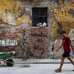 Un hombre pasa junto a un grafiti que dice "Tienes que ser feliz" del artista cubano Mr. Sad en La Habana. Hace más de un año, un grafiti simple y contundente que dice "Tienes que ser feliz" comenzó a aparecer en las desgastadas paredes de La Habana. El mensaje aparentemente inocente se ha convertido en un eco de reflexión para muchos y en una inspiración para los jóvenes creadores cubanos. | Foto:YAMIL LAGE / AFP