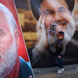 Un niño pasa junto a una fotografía del líder libanés de Hezbolá, Hassan Nasrallah (derecha), y del comandante de la Guardia Revolucionaria iraní, Qasem Soleimani, durante una manifestación en la zona de Shula, al oeste de Bagdad. | Foto:AHMAD AL-RUBAYE / AFP