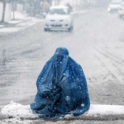 Una mujer afgana vestida con burka busca limosna en una calle durante la primera nevada intensa de este invierno en Kabul. | Foto:WAKIL KOHSAR / AFP