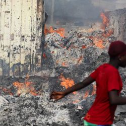 Una mujer pasa junto a un incendio en el mercado de ropa de segunda mano de Kantamanto, en Accra, Ghana. | Foto:Nipah Dennis / AFP