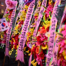 Una persona se encuentra junto a flores y mensajes en apoyo al presidente de Corea del Sur destituido, Yoon Suk Yeol, durante una manifestación cerca de su residencia en Seúl. Miles de manifestantes surcoreanos desafiaron una tormenta de nieve por el presidente suspendido Yoon Suk Yeol, quien todavía se resistía al arresto por un intento fallido de instaurar la ley marcial menos de 48 horas antes de que expirara la orden judicial. | Foto:Philip Fong / AFP