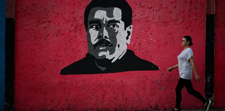 Una mujer pasa junto a un mural que representa al presidente venezolano Nicolás Maduro en Caracas. El 10 de enero, Maduro prestará juramento para un tercer mandato de seis años, después de rechazar las acusaciones de que robó las elecciones de julio al candidato opositor ahora exiliado Edmundo González Urrutia, quien afirma haber ganado de manera aplastante.