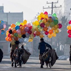 Los vendedores de globos afganos caminan con sus bicicletas para buscar clientes, cerca de un mercado en Kabul. | Foto:WAKIL KOHSAR / AFP