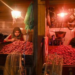 Una vendedora de cebollas usa su teléfono móvil en un mercado tradicional de Surabaya, Indonesia. | Foto:JUNI KRISWANTO / AFP