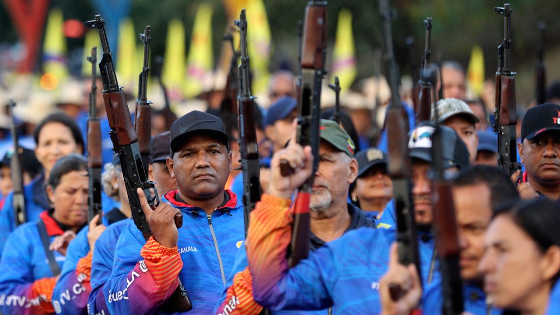 Members of the Bolivarian Militia and supporters of the Maduro government raise up assault rifles as they take part in a rally during a swearing-in march for combatant forces in Caracas on January 7, 2025.