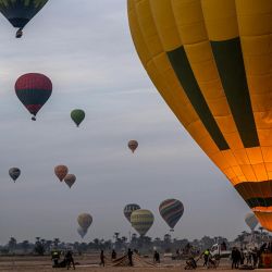 Los turistas reciben ayuda para subir a la cesta de un globo aerostático antes de volar sobre la orilla oeste del río Nilo en la ciudad de Luxor, en el sur de Egipto. | Foto:Khaled Desouki / AFP