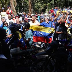Manifestantes antigubernamentales gritan consignas mientras partidarios del presidente venezolano Nicolás Maduro pasan en motocicletas durante una protesta convocada por la oposición en vísperas de la investidura presidencial, en Caracas. | Foto:PEDRO MATTEY / AFP