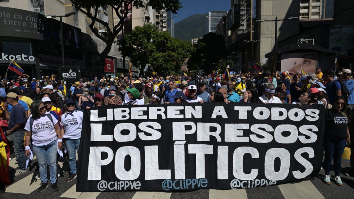 Demonstrators hold a banner demanding for the release of all political prisoners during a protest called by the opposition on the eve of the presidential inauguration, in Caracas on January 9, 2025. 