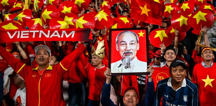 Los hinchas levantan un sombrero cónico asiático con los colores vietnamitas y un retrato de Ho Chi Minh antes del inicio del partido de ida de la final de la Copa Eléctrica de la ASEAN 2024 entre Vietnam y Tailandia en el Estadio Viet Tri en la provincia de Phu Tho.