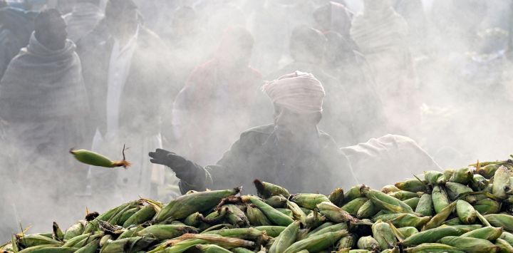 Un vendedor se prepara para cargar maíz tostado en carros en un mercado de Lahore, Pakistán.