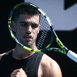 El español Carlos Alcaraz lanza su raqueta al aire durante una sesión de entrenamiento antes del torneo de tenis Abierto de Australia en Melbourne. | Foto:DAVID GRAY / AFP
