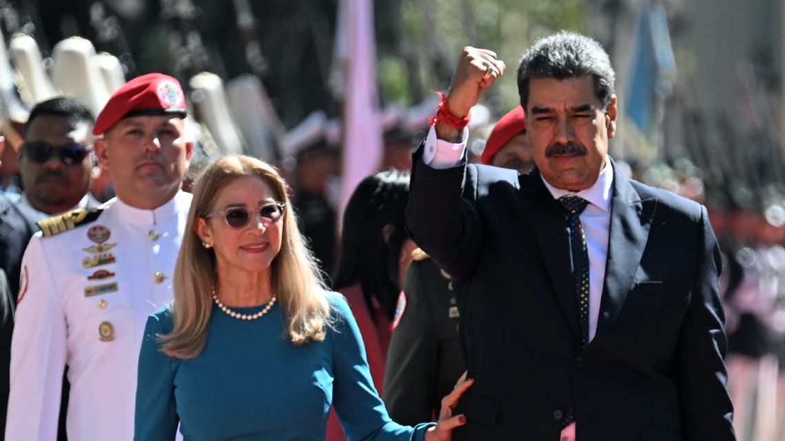 Venezuela's President Nicolás Maduro gestures next to First Lady Cilia Flores on arrival at the Capitolio -house of the National Assembly- for the presidential inauguration, in Caracas on January 10, 2025.