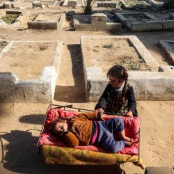Una niña mece una cuna de metal improvisada donde yace un niño, mientras familias desplazadas por el conflicto se refugian junto a tumbas en un cementerio en Deir el-Balah, en el centro de la Franja de Gaza, en medio de la guerra en curso en el territorio palestino entre Israel y Hamás. | Foto:Eyad Baba / AFP