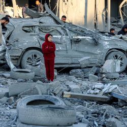 Hombres y niños junto a un automóvil destruido entre escombros y escombros junto a un edificio derrumbado en el lugar del bombardeo israelí en un bloque residencial en la calle Jalaa en la ciudad de Gaza, en medio de la guerra en curso en el territorio palestino entre Israel y Hamás. | Foto:OMAR AL-QATTAA / AFP