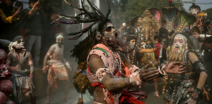 Devotos hindúes untados con ceniza bailan durante una procesión religiosa antes del festival Maha Kumbh Mela en Prayagraj, India.