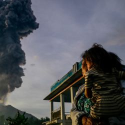 Una mujer y un niño observan las cenizas volcánicas que se elevan al aire durante la erupción del monte Ibu, como se ve desde la aldea de Duono en West Halmahera, provincia de Maluku del Norte, Indonesia. | Foto:AZZAM / AFP