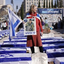 Un manifestante se encuentra frente a la Corte Suprema en Jerusalén, entre ataúdes simulados cubiertos con banderas israelíes, para protestar contra el alto el fuego con Hamás. | Foto:JOHN WESSELS / AFP
