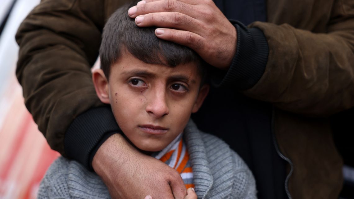 A Palestinian boy is comforted as he mourns the death of a loved one killed an Israeli strike the previous night, outside Nasser Hospital in Khan Yunis, in the southern Gaza Strip, on January 16, 2025, amid the ongoing war in the Palestinian territory between Israel and Hamas.