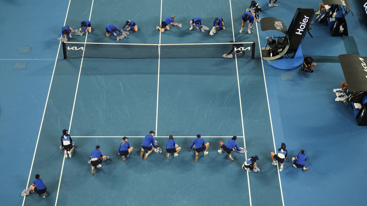 Los recogepelotas secan la cancha durante una demora por lluvia en el partido individual masculino entre el serbio Novak Djokovic y el portugués Jaime Faria en el cuarto día del torneo de tenis Abierto de Australia en Melbourne. | Foto:Adrian Dennis / AFP