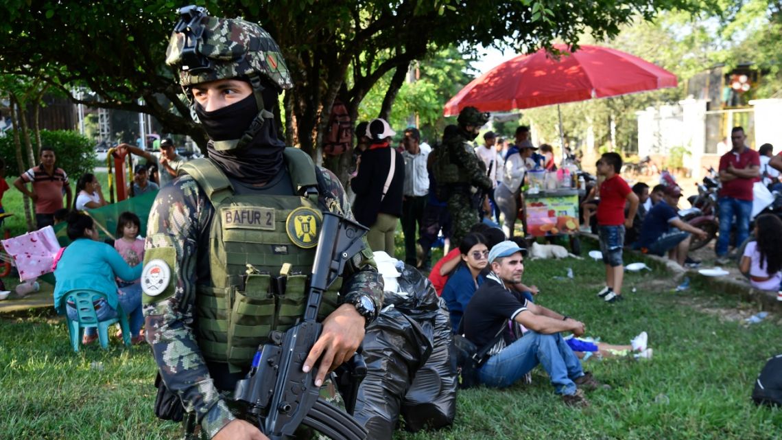 Colombian army soldiers stand guard next to displaced people from recent clashes between armed groups arriving in the municipality of Tibu, Norte de Santander Department, Colombia, on January 18, 2025.