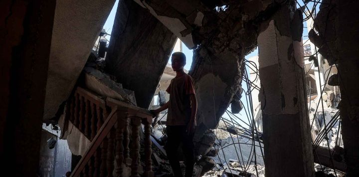 Un niño se encuentra en la escalera de un edificio gravemente dañado en Rafah, en el sur de la Franja de Gaza. Foto de Eyad BABA / AFP