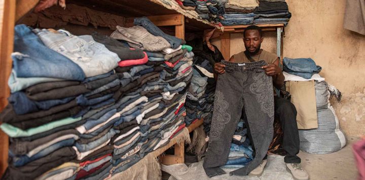 Un vendedor dobla pantalones en su tienda del mercado Mixebo de Cotonú. Foto de Eustache Ahomagnon / AFP