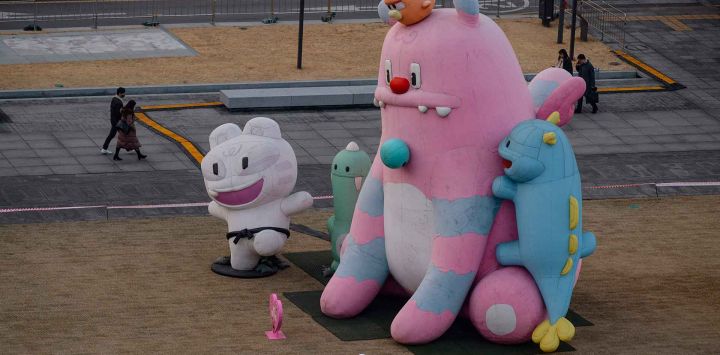 Una persona envuelta en una bandera de Corea del Sur pasa junto a la mascota de la ciudad, Hechi, en Seúl. Foto de ANTHONY WALLACE / AFP