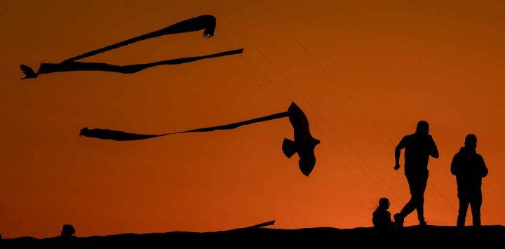 La gente observa a los participantes volar cometas durante el Festival de Cometas de Qatar en Doha. Foto de Karim JAAFAR / AFP