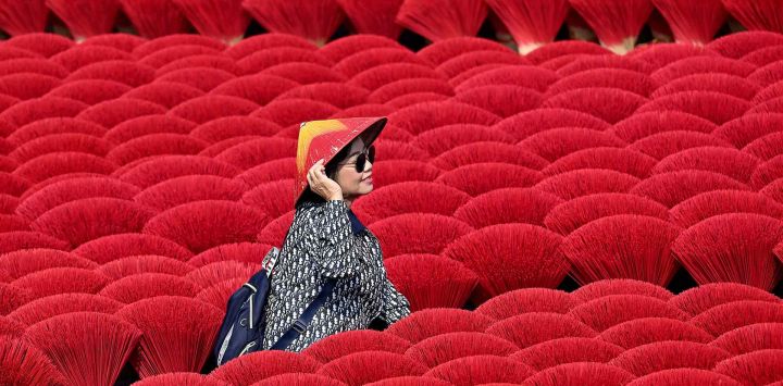  Un turista posa frente a unas varillas de incienso que se secan en un Un turista posa frente a unas varillas de incienso que se secan en un patio de la aldea Quang Phu Cau, en las afueras de Hanoi. Foto de Nhac NGUYEN / AFP, en las afueras de Hanoi. Foto de Nhac NGUYEN / AFP