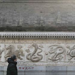  Un hombre observa la figura de la serpiente en el muro de piedra del zodíaco chino, durante su visita al Templo Taoísta Baiyun. Foto de Pedro PARDO / AFP | Foto:AFP