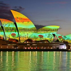 Las velas de la Ópera de Sídney se iluminan con la obra de arte “River Life” del artista wiradjuri James P. Simon en el Día de Australia en Sídney. | Foto:AYUSH KUMAR / AFP