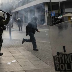 Un agente de la policía antidisturbios griega persigue a un manifestante durante una manifestación por las víctimas de un accidente de tren mortal en 2023, que se cobró 57 vidas, cerca del edificio del Parlamento, en Atenas. | Foto:ANGELOS TZORTZINIS / AFP