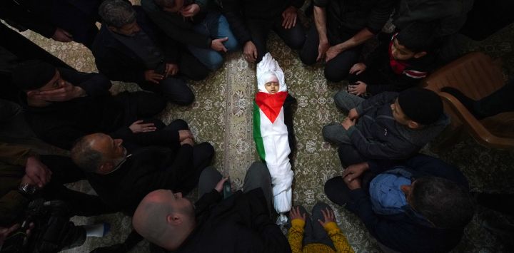 Los dolientes rodean el cuerpo envuelto en una bandera de Laila al-Khatib, de dos años, mientras yace en una mezquita, un día después de que sucumbiera a sus heridas luego de recibir un disparo durante una redada militar israelí en Jenin, en la Cisjordania ocupada, antes de su funeral.