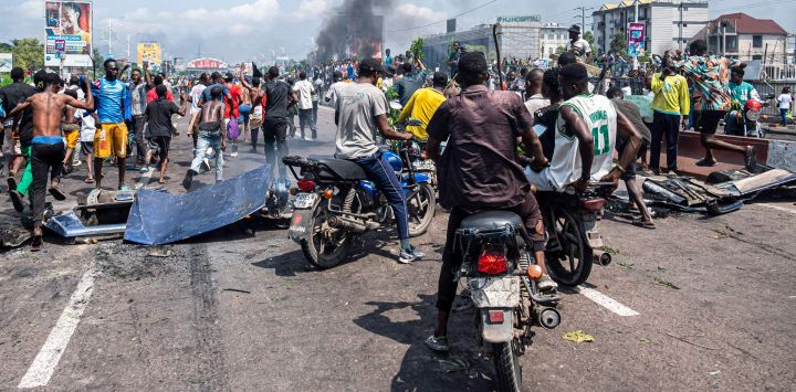 Manifestantes se reúnen mientras se elevan columnas de humo de neumáticos en llamas durante una manifestación contra el conflicto que se intensifica en el este de la República Democrática del Congo en Kinshasa.