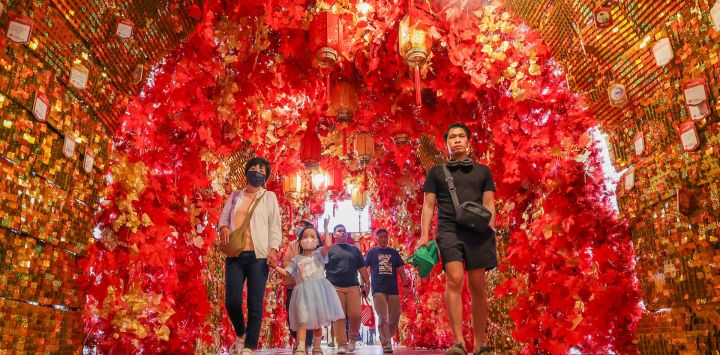 Personas caminan por un pasillo lleno de decoraciones de la Fiesta de la Primavera en un centro comercial en el Barrio Chino, en Manila, Filipinas.