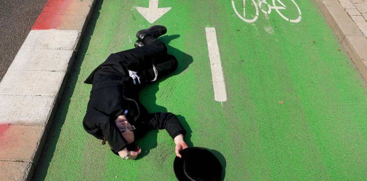 Un manifestante se encuentra tumbado en un carril bici mientras la policía israelí dispersa una sentada de hombres judíos ultraortodoxos contra una sentencia de un alto tribunal israelí que les obliga a ser reclutados para el servicio militar, frente a una oficina de reclutamiento del ejército en la ciudad de Kiryat Ono, cerca de Tel Aviv.